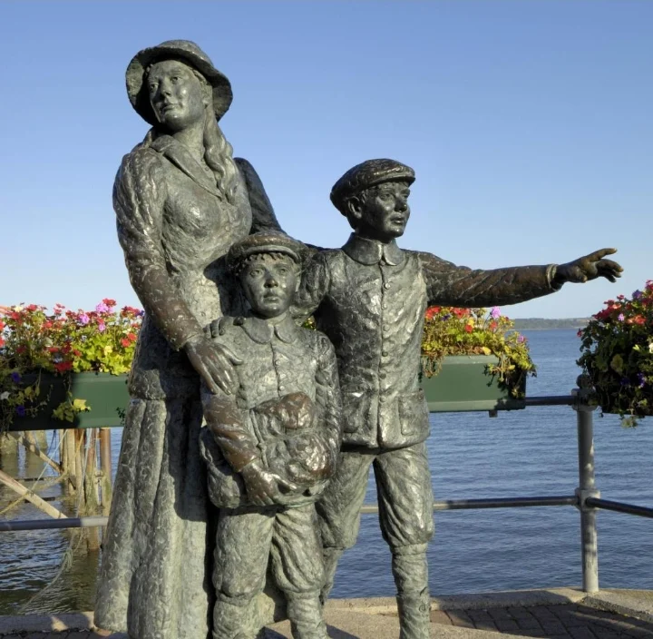 A bronze sculpture of a young woman with her two younger brothers on a waterfront; one boy points out to sea